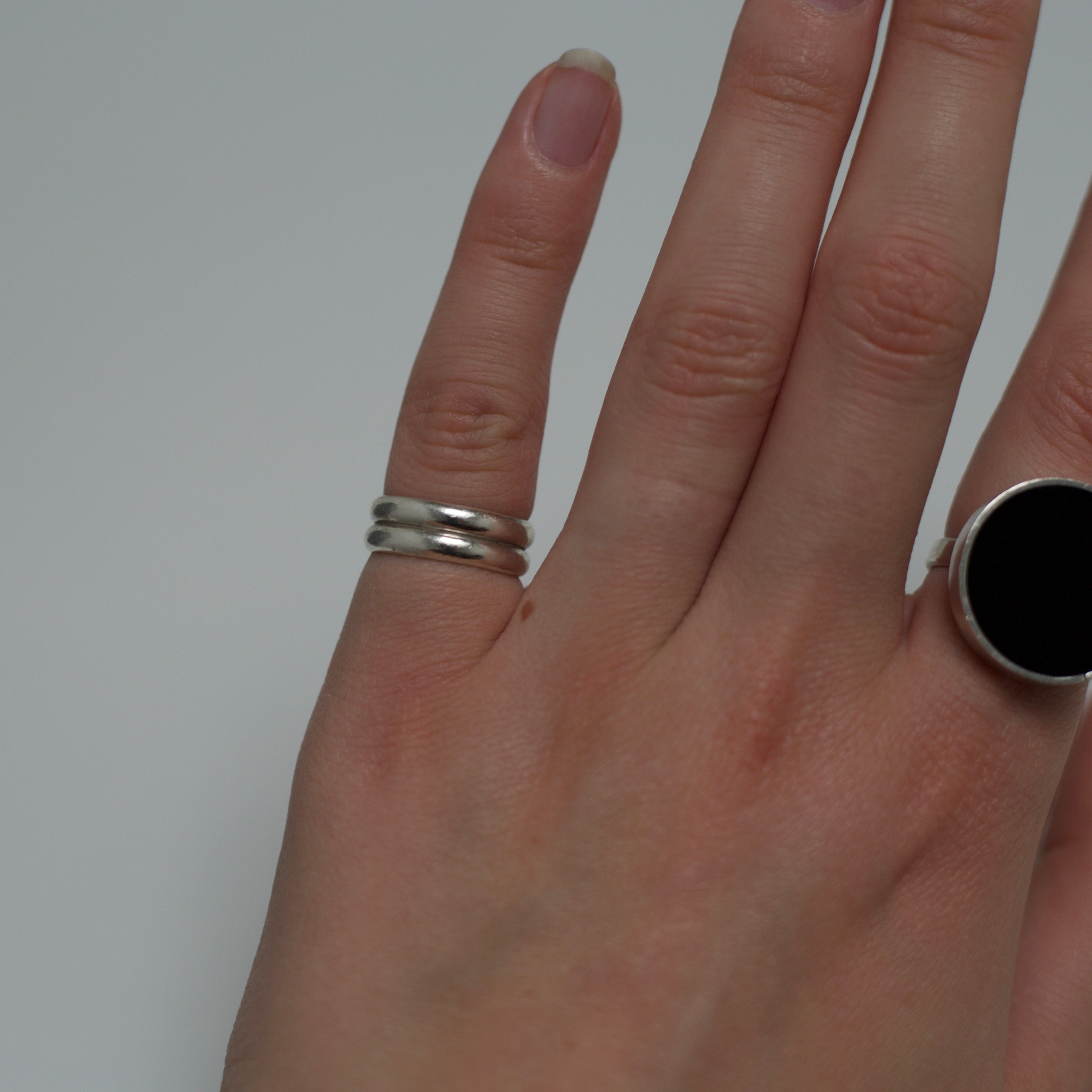 Hand wearing two rings with a plain background