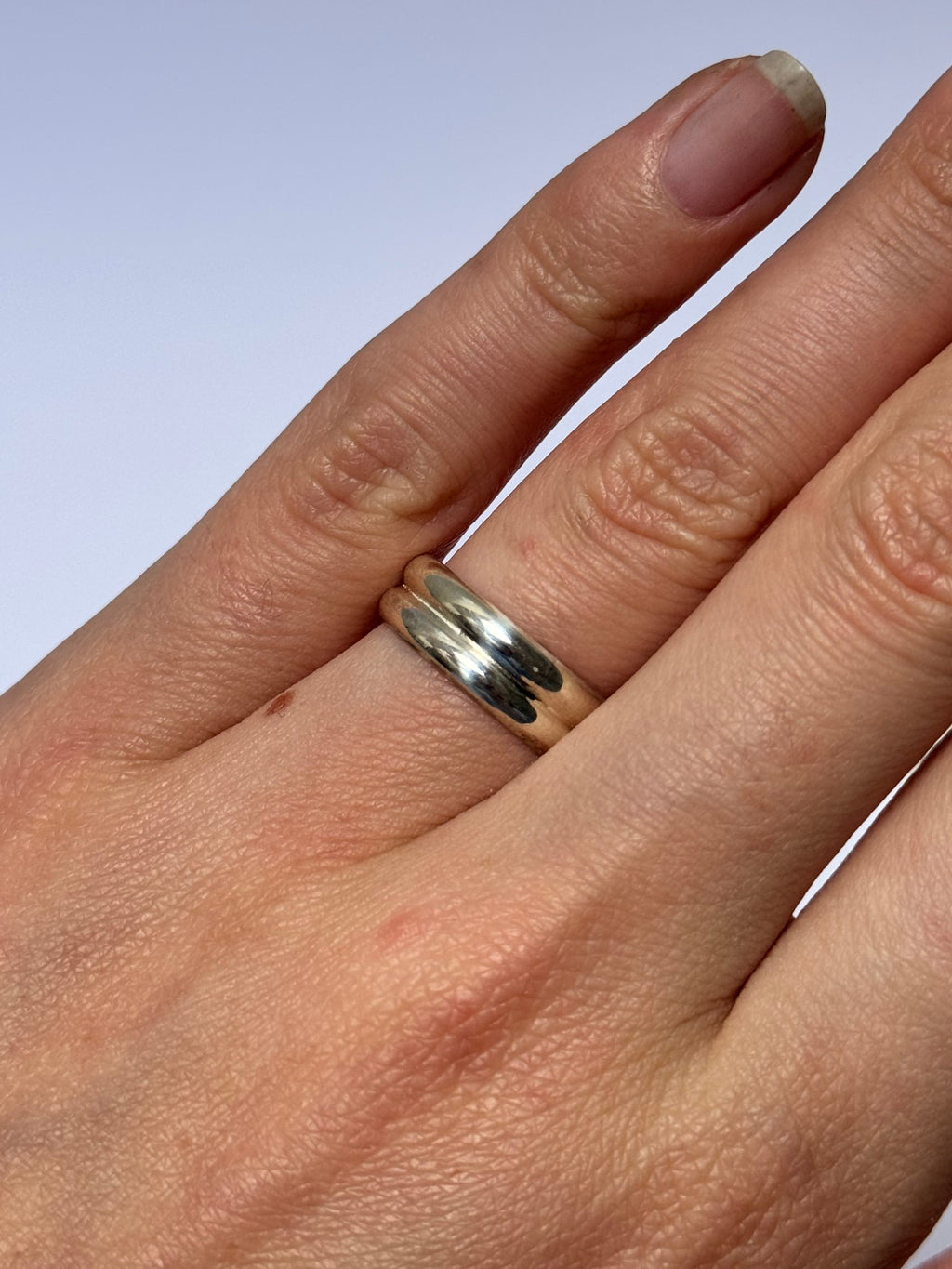 Hand wearing a silver ring on a light background