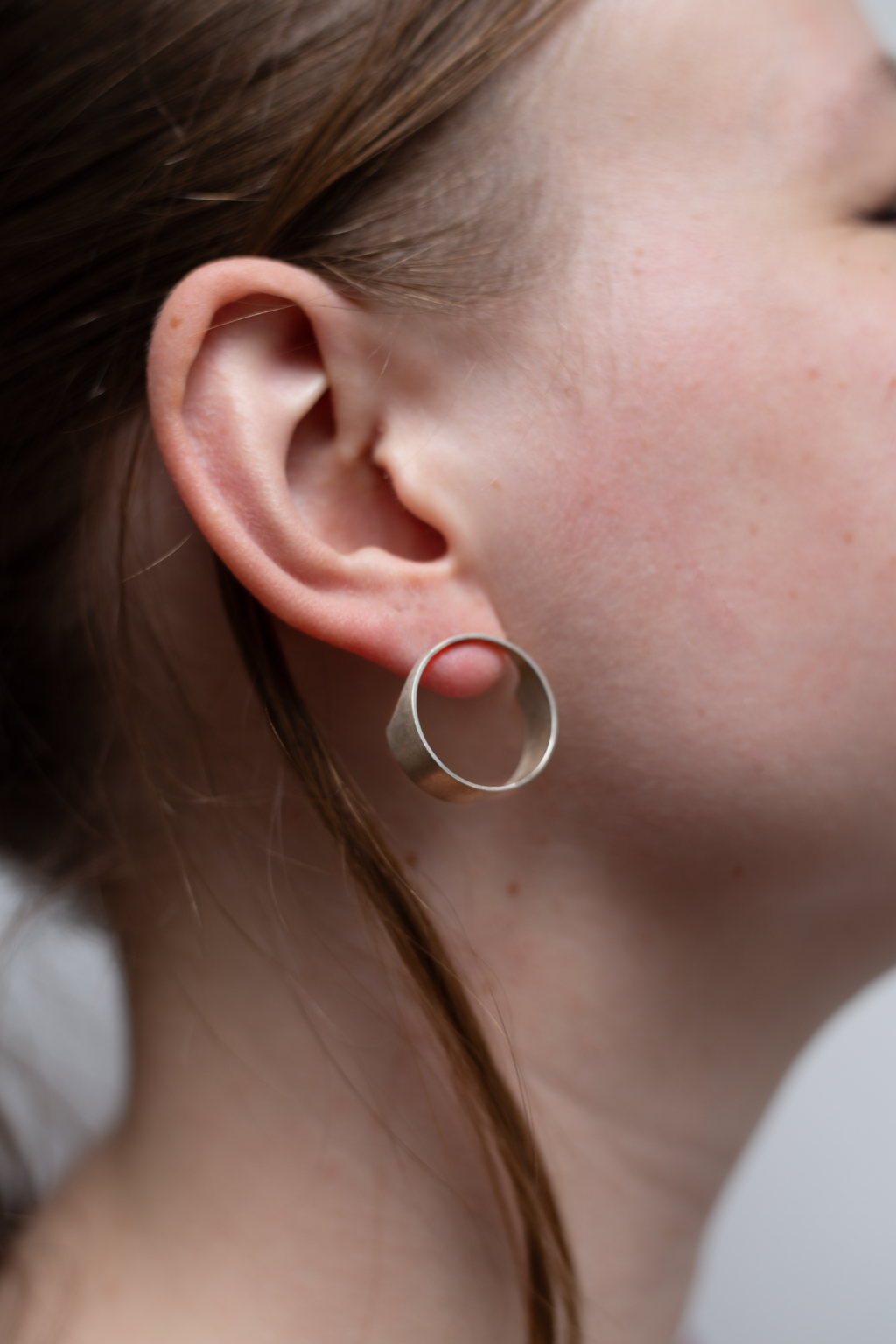 Close-up of a person wearing a silver hoop earring.