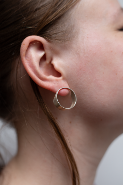 Close-up of a person wearing a silver hoop earring.