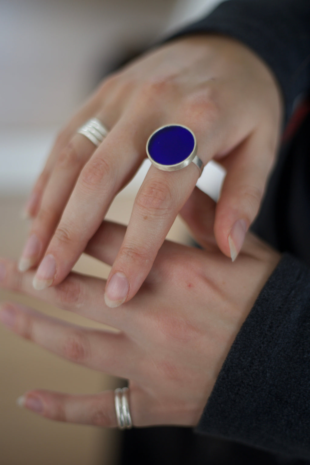 Close-up of hands wearing silver rings with a blue acrylic.
