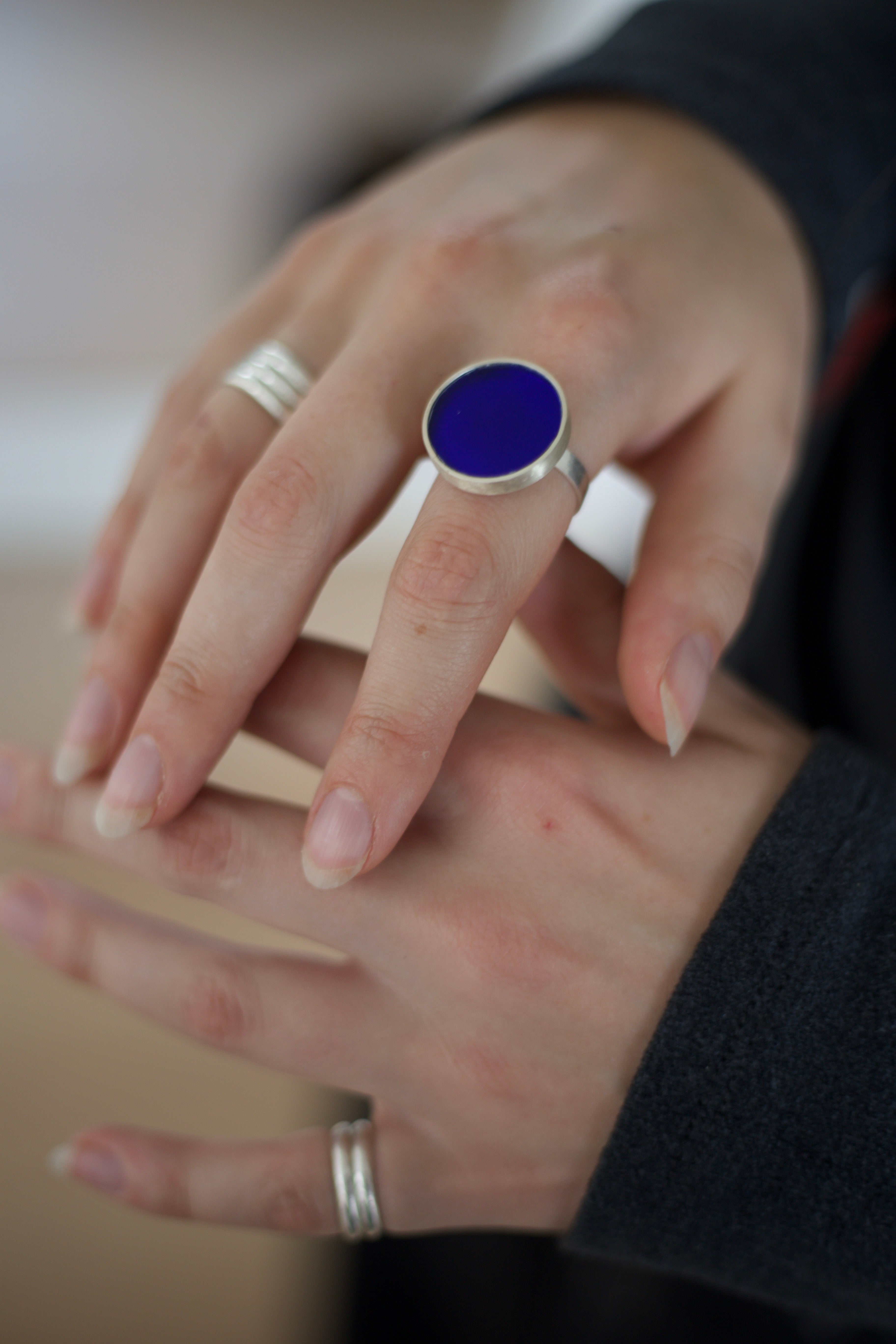 Close-up of hands wearing silver rings with a blue acrylic.