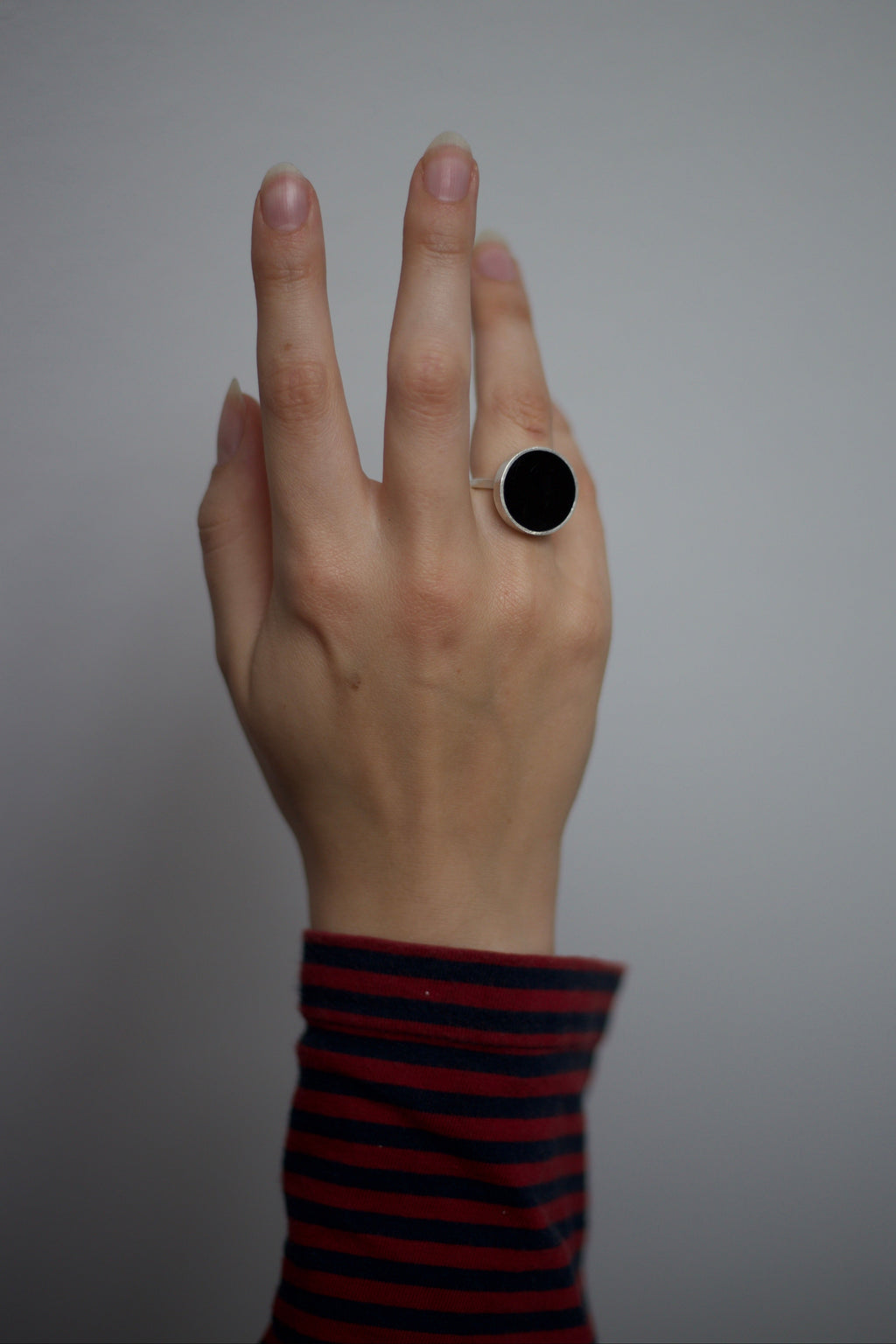 Hand with a black ring on a plain background