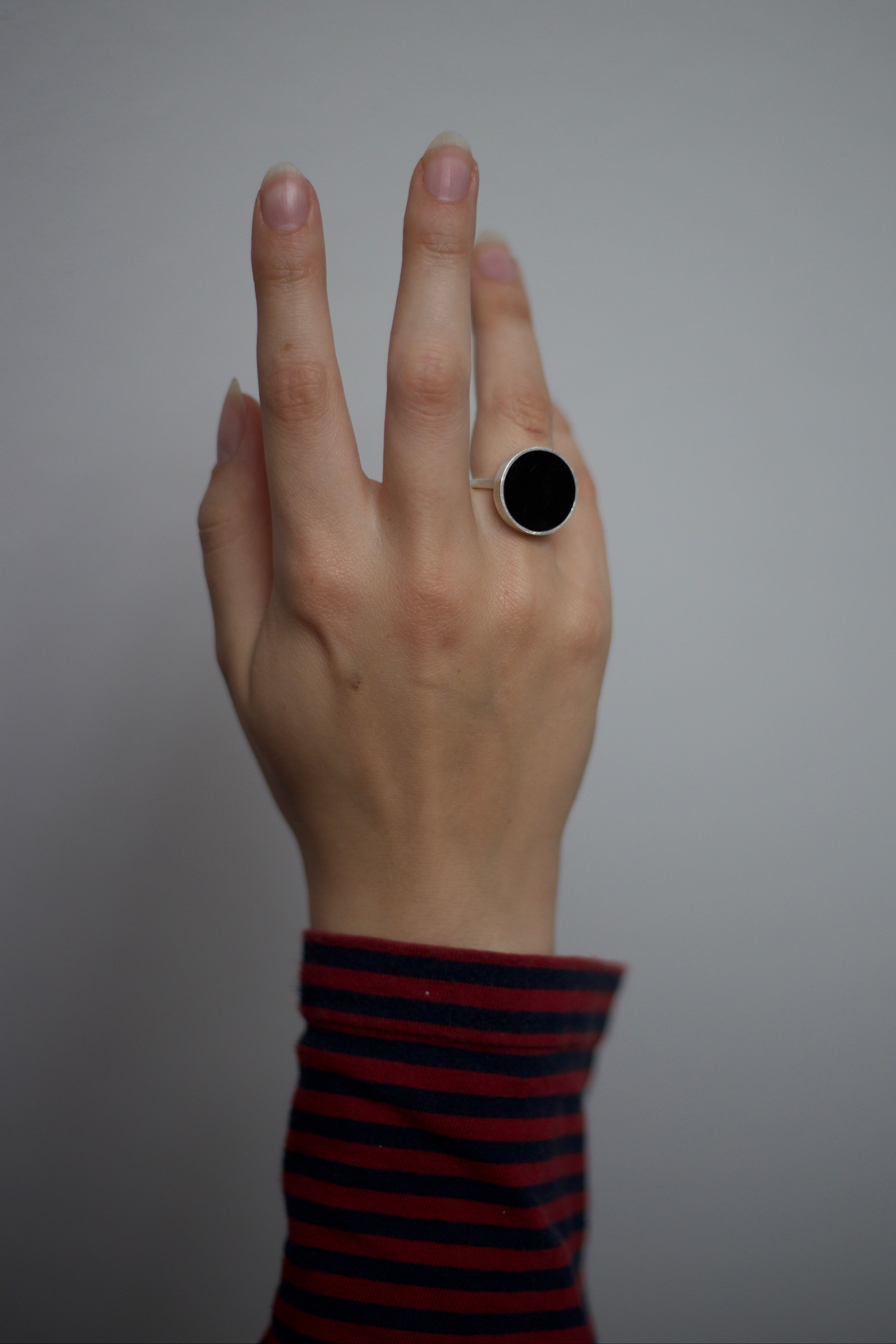 Hand with a black ring on a plain background