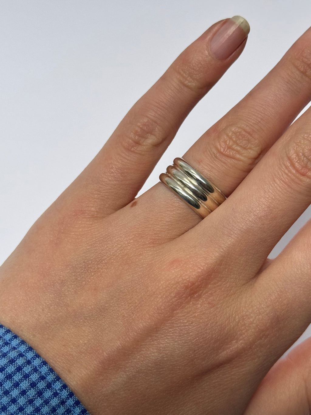 Hand wearing a silver ring on a white background